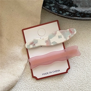 Détail de barrettes à cheveux ondulées en acétate avec texture marbrée sur carte