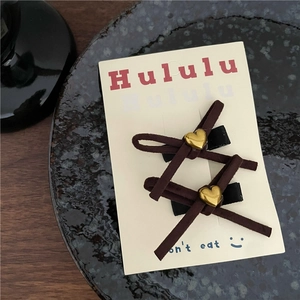 Détail de barrettes à cheveux en velours marron avec cœur doré sur carte de support