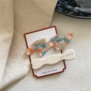 Gros plan de barrettes en acétate ondulées avec texture marbre et texte doré