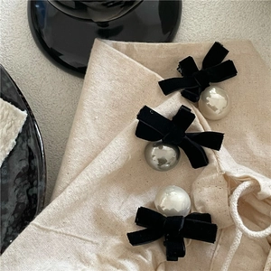 Elegant black velvet bow hair clips set with imitation pearl details on beige canvas bag