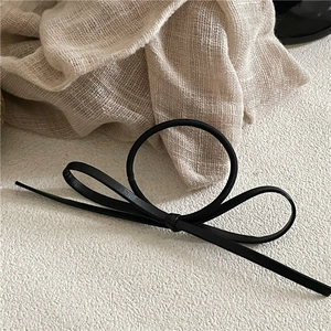 Detail of the elegant black PU leather bow hair tie with a minimalist French retro style