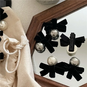 Elegant velvet bow hair clips with pearls and storage bag shown in a mirror reflection