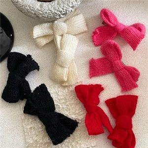 Draufsicht auf Strickschleifen-Haarspangen in Schwarz, Weiß und Rot auf Struktur
