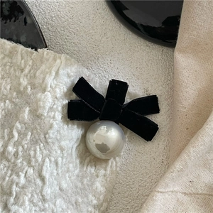 Close-up of elegant black velvet bow hair clip with a large pearl on knit fabric