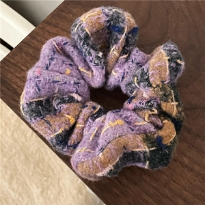 Close-up of thick checkered wool scrunchie featuring purple and camel knit texture