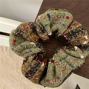 Close-up detail of multi-colored tweed scrunchie showing the woven texture and plaid pattern