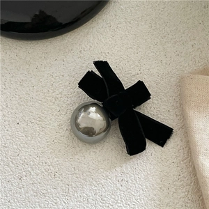 Macro detail of black velvet bow hair clip with polished silver metal bead detail