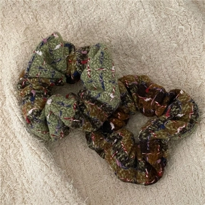 Detailed view of tweed plaid scrunchies in dark green and brown colors, two-piece set