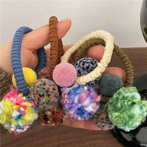 Detail of colorful pompom hair ties featuring thick elastic knit and soft plush balls