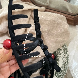Dettaglio della pinza per capelli nera floccata con sfere rosse per capelli folti
