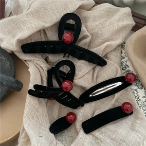 Dettaglio macro di set di fermagli neri floccati con eleganti perline rosso intenso