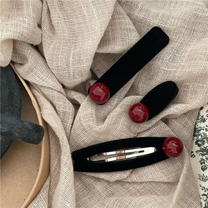 Set di fermagli per capelli in velluto nero con perline rosse su sfondo in tessuto rustico