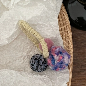 Detail of soft colorful plush balls and elastic knitted hair tie on a bamboo tray