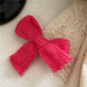 Detailaufnahme einer handgestrickten rosepinkfarbenen Schleife mit Wollstruktur