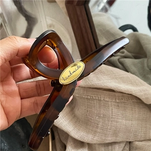 Close-up of tortoise shell hair claw clip featuring a golden handmade metal plaque