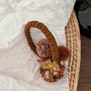 Detailed close-up of brown elastic hair tie with colorful knit plush balls on white paper