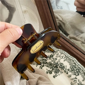 Detailed macro view of retro tortoiseshell hair claw clip with golden handmade metal plate