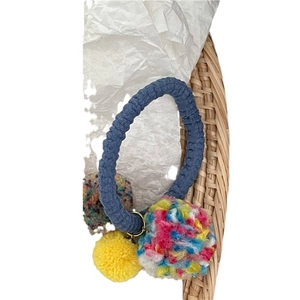 Colorful pom pom hair tie with blue textured elastic cord and three vibrant plush balls