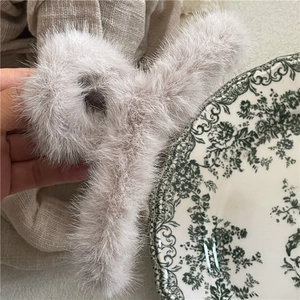 Detail shot of a soft plush shark hair claw clip in a warm creamy beige tone