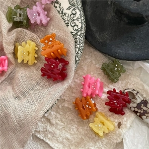 Détail de mini pinces à cheveux ours colorées avec strass brillants sur tissu doux