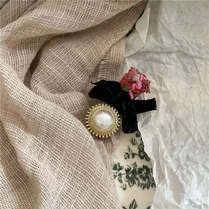 Close-up of retro fuchsia fabric bow hair clip with faux pearl button and velvet detail