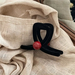Dettaglio molletta per capelli floccata nera con una perla decorativa rossa vivace