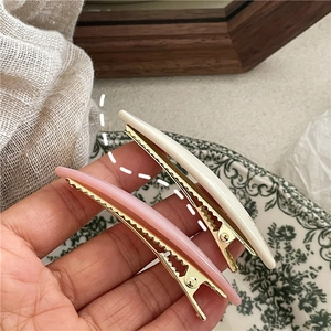 Detail of pink and cream acetate willow leaf hair clips on a golden metal base