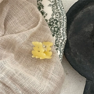 Détail d'une pince à cheveux ours jaune translucide sur une assiette florale