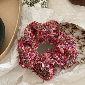 Close-up of woven multicolor wool scrunchie with rich texture and vibrant pink tones