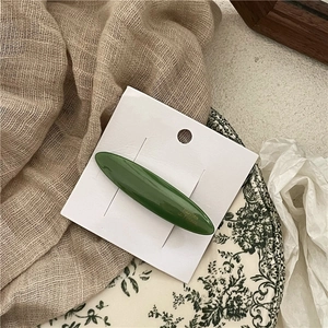Close-up of olive green acetate hair clip with French branding on a display card