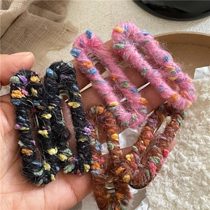 Barrettes à cheveux ovales enveloppées de laine colorée présentées sur une paume