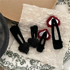 Gros plan de jolies barrettes en peluche en forme de cœur rouge et noir, texture velours