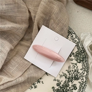 Detail of a pearlescent pink acetate hair clip displayed on a minimalist white card