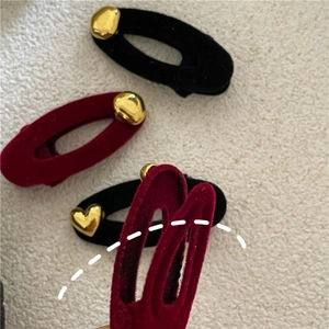 Close-up of velvet oval hair clips in black and wine red with gold heart rhinestones