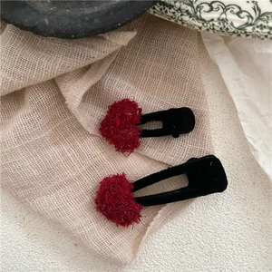 Détail de pinces à cheveux en peluche rouge avec paillettes sur base floquée noire