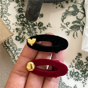 Detail of velvet oval hair clips with golden heart accents in black and burgundy