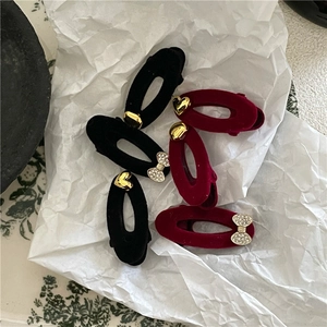 Detailed macro view of black and wine red flocked oval hair clips with heart and bow accents