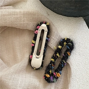 Détail de barrettes ovales en laine avec mini pompons colorés sur un tissu beige doux