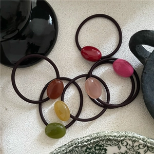 Pastel cream-colored oval pebble elastic hair ties with colorful beaded resin charms