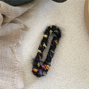 Détail d'une barrette à cheveux faite main avec du fil noir et des perles de laine colorées