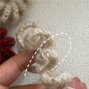 Gros plan sur l'élastique spirale en laine tressée aux tons beige et rouge foncé