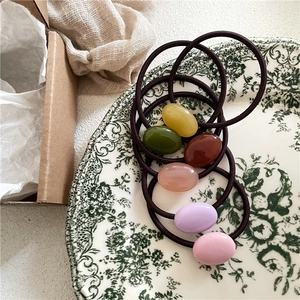 Close-up of six colorful oval resin beads on high-elasticity braided hair ties