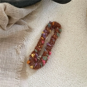 Détail d'une pince à cheveux ovale en laine avec pompons colorés pour styles d'automne hiver