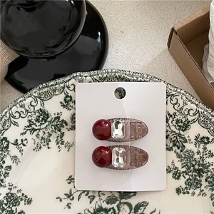 Détail de pinces à cheveux vintage avec perles rouges et cristaux sur une assiette décorée