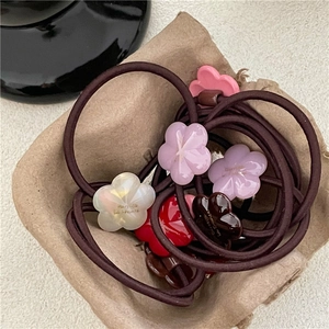 Floral acetate hair ties in various colors with high elastic bands on a rustic tray
