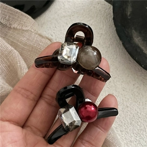 Detail of mini hair claws featuring tortoiseshell patterns, red beads, and crystal accents