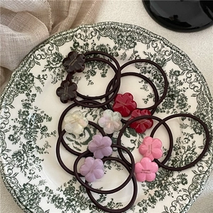 Floral acetate hair ties in five colors displayed on a vintage ceramic plate