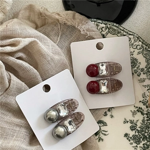 Gros plan de barrettes à perles et strass sur une assiette décorative et tissu