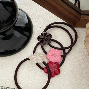 Detail of four acetate flower hair ties in brown, pink, beige, and red colors