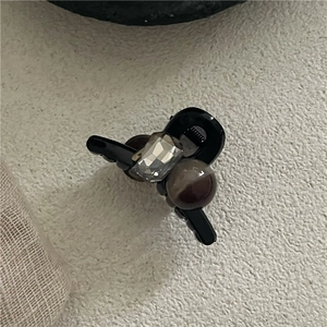 Detail of a mini black hair claw clip featuring a square gemstone and marble-textured bead